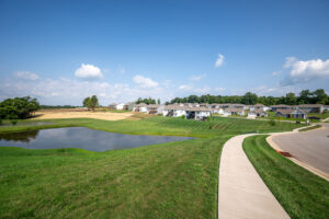 blue lake with green grass and walking trail in front of homes in Knob Hill