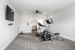 workout room with exercise equipment and tv in the ellingsworth commons clubhouse